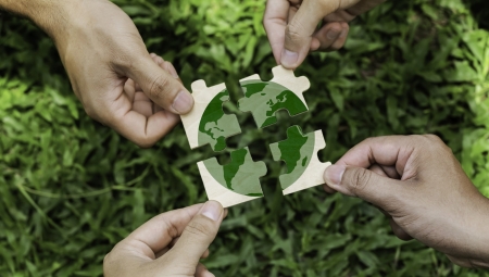 four people holding pieces of a jigsaw of the earth