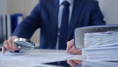 man with magnifying glass looking at documents